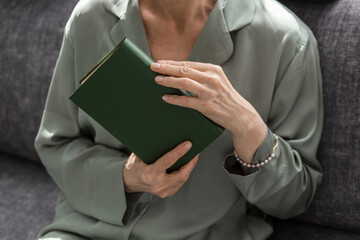 Close-up of woman holding book on couch