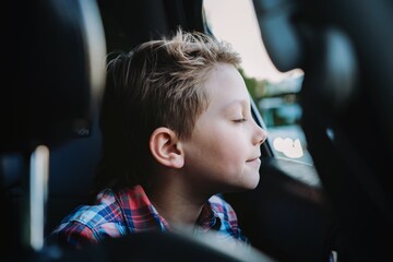 Handsome caucasian boy travelling by car sitting in child seatRecreation concept