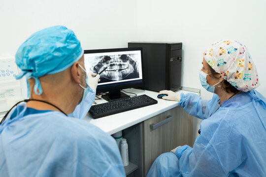 Dentists analyzing x-ray on computer screen at clinic