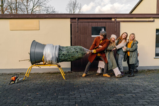 Father dragging Christmas tree with family at footpath