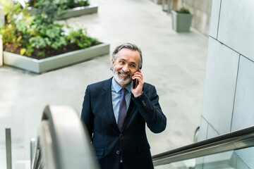 Happy mature businessman with beard talking on mobile phone