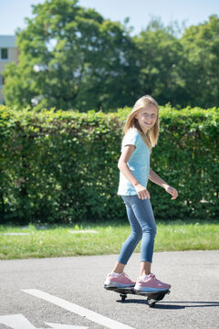 Smiling blond girl skateboarding on traffic course