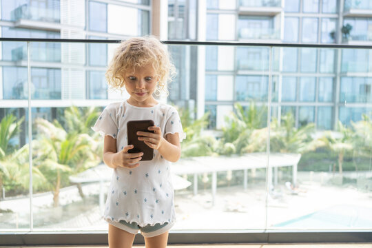 Girl with raised eyebrows taking selfie through smart phone on balcony