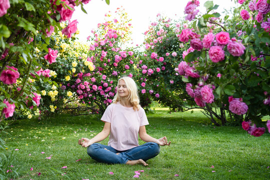 Woman with eyes closed meditating amidst rose garden