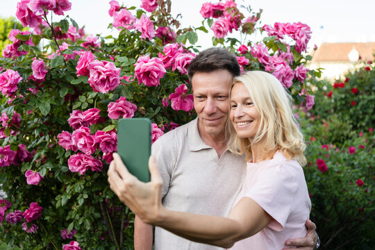 Smiling couple taking selfie in rose garden
