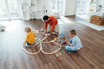 Father and son playing with toy train set at home