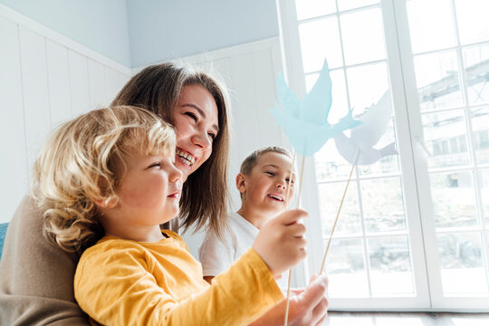 Happy mother and son playing with origami birds at home