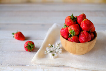 Fresh ripe red strawberries in wooden cup and whitecloth on wooden background, natural rustic food,fruit