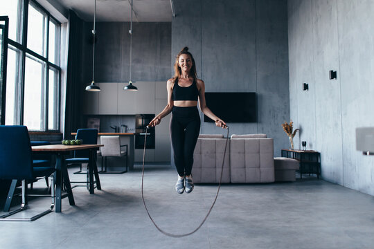 Fit woman with jump rope at home doing skipping workout.