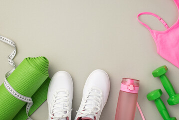 Fitness accessories concept. Top view photo of white shoes pink sports bra bottle of water tape measure green exercise mat and dumbbells on isolated pastel grey background with copyspace
