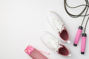 Fitness concept. Top view photo of white sneakers pink bottle of water and skipping rope on...
