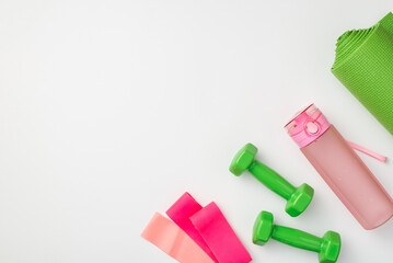 Fitness accessories concept. Top view photo of green sports mat dumbbells pink bottle of water and...