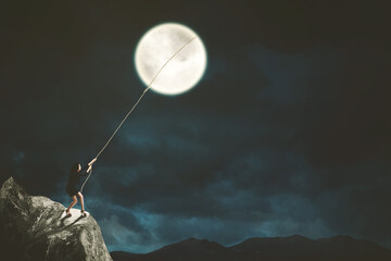 Businesswoman pulling a bright moon in night sky