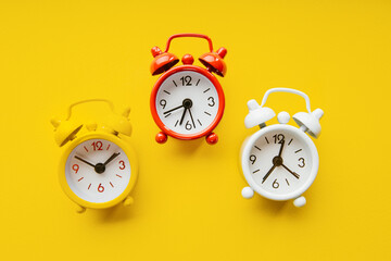 Colourful alarm clocks on a yellow background. Close-up
