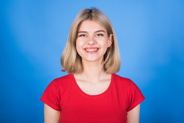Portrait of a happy, young and attractive blonde girl in casual clothes isolated on a blue studio background.