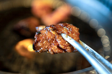 トングで持ち上げる中落ちカルビ  焼肉　アップ