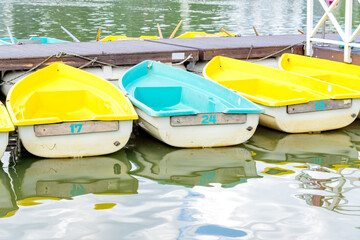 Fototapeta na wymiar Row of blue and yellow boats parked at the pier of the lake. boat station. Tourist resort on the coast of river
