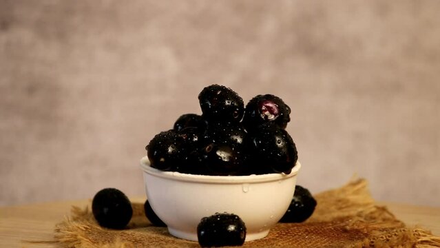 Beautiful jamun fruit rotates in circles with water drop close up view,turning blueberries with white bowl