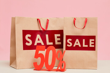 Close-up of shopping bags with Sale lettering and fifty percent tablet for store display window