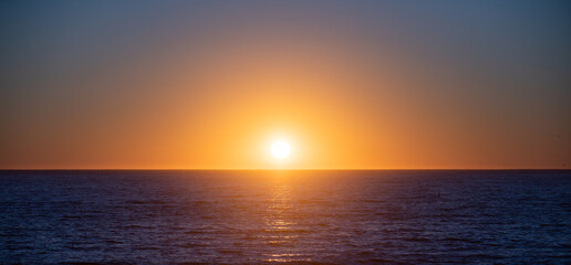 Sunset over sea with golden dramatic sky panorama. Calm sea with sunset sky. Ocean and sky background.