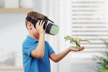 Boy with VR glasses projects a dinosaur on his arm. The concept of using virtual reality in...