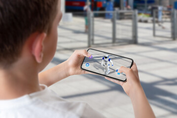 Boy programs and controls the robot on the street via augmented reality technology concept