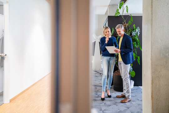 Businessman and businesswoman sharing digital tablet in office