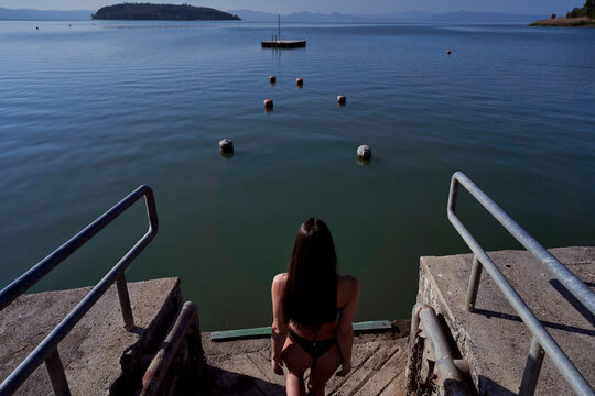 Woman in bikini walking towards lake on sunny day