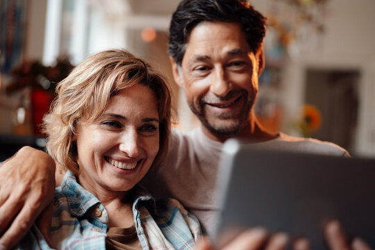Happy woman sharing tablet PC with man at home