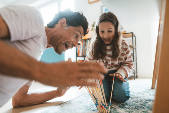 Surprised father and daughter playing mikado at home