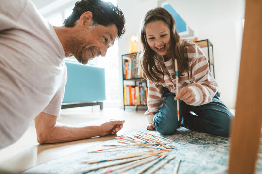 Cheerful daughter with father playing mikado at home