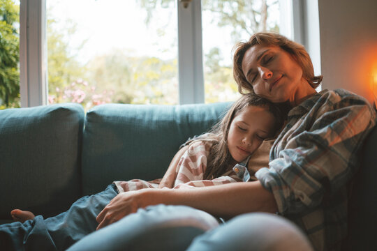Mother and daughter with eyes closed on sofa at home