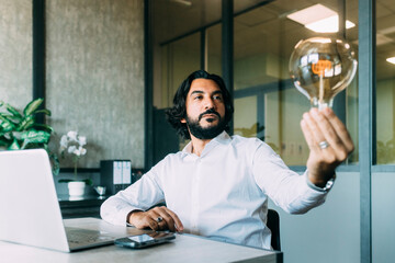 Businessman analyzing light bulb at office