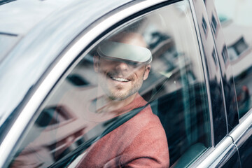 Smiling man wearing virtual reality headset sitting in car