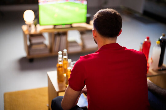 Young Man Watching Football Match At Home