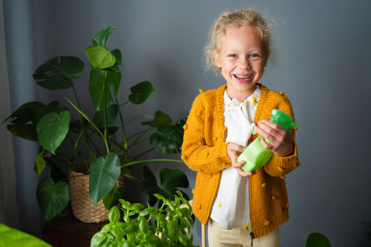 Happy Girl Holding Spray Bottle In Living Room