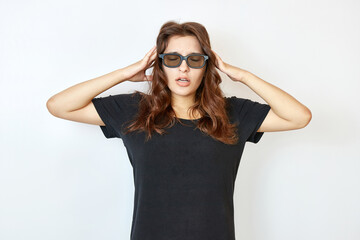 Beautiful girl in glasses and a black T-shirt holds his hands behind his head.