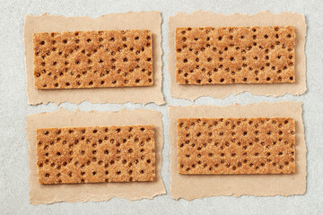 Set of rye crunchy crispbread on craft paper pieces with torn edges. Dietetic Crackers. Food background