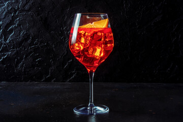 Aperol cocktail with a fresh orange slice, a side view on a black slate background with a place for text, Italian summer cold drink