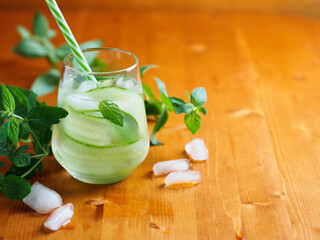 A glass of cucumber cold detox lemonade with mint and lemon on a wooden table