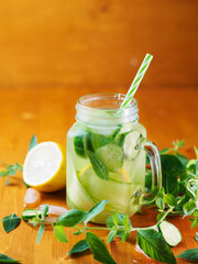 Summer detox cucumber water with lemon and mint in a jar on a wooden table