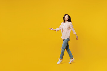 Full size side view young happy smiling woman she 30s wear striped shirt white t-shirt walking going strolling look camera isolated on plain yellow background studio portrait People lifestyle concept