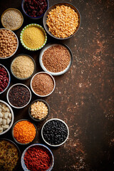 Various superfoods in smal bowls on dark rusty background