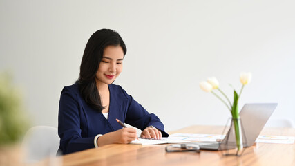 Charming young business entrepreneur sitting at her spacious office and working with financial...