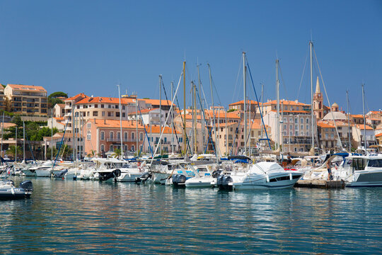 View across marina to the town, yachts and motor boats reflected in tranquil water, Calvi, Haute-Corse