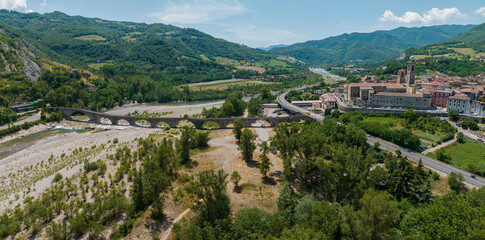 Fototapeta na wymiar Aerial view of Bobbio, a town on the Trebbia river. Bridge. Piacenza, Emilia-Romagna. Details of the urban complex, roofs and bell towers of the town between the valleys of the Apennines. Italy. Droug