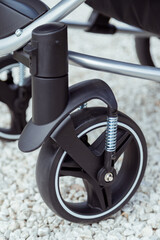 Baby stroller wheel with spring shock absorber close-up, baby stroller on details in summer