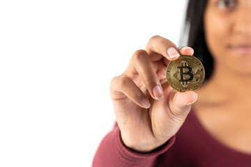 Young black woman showing a bitcoin coin to the camera on a white background.