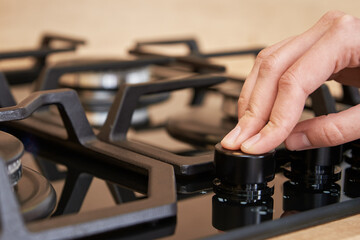 Female hand adjusting temperature on gas hob control panel, Woman using gas stove, Modern household appliances