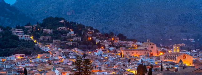 View of churches and rooftops of Pollenca with mountain in background at dusk, Pollenca, Majorca, Balearic Islands